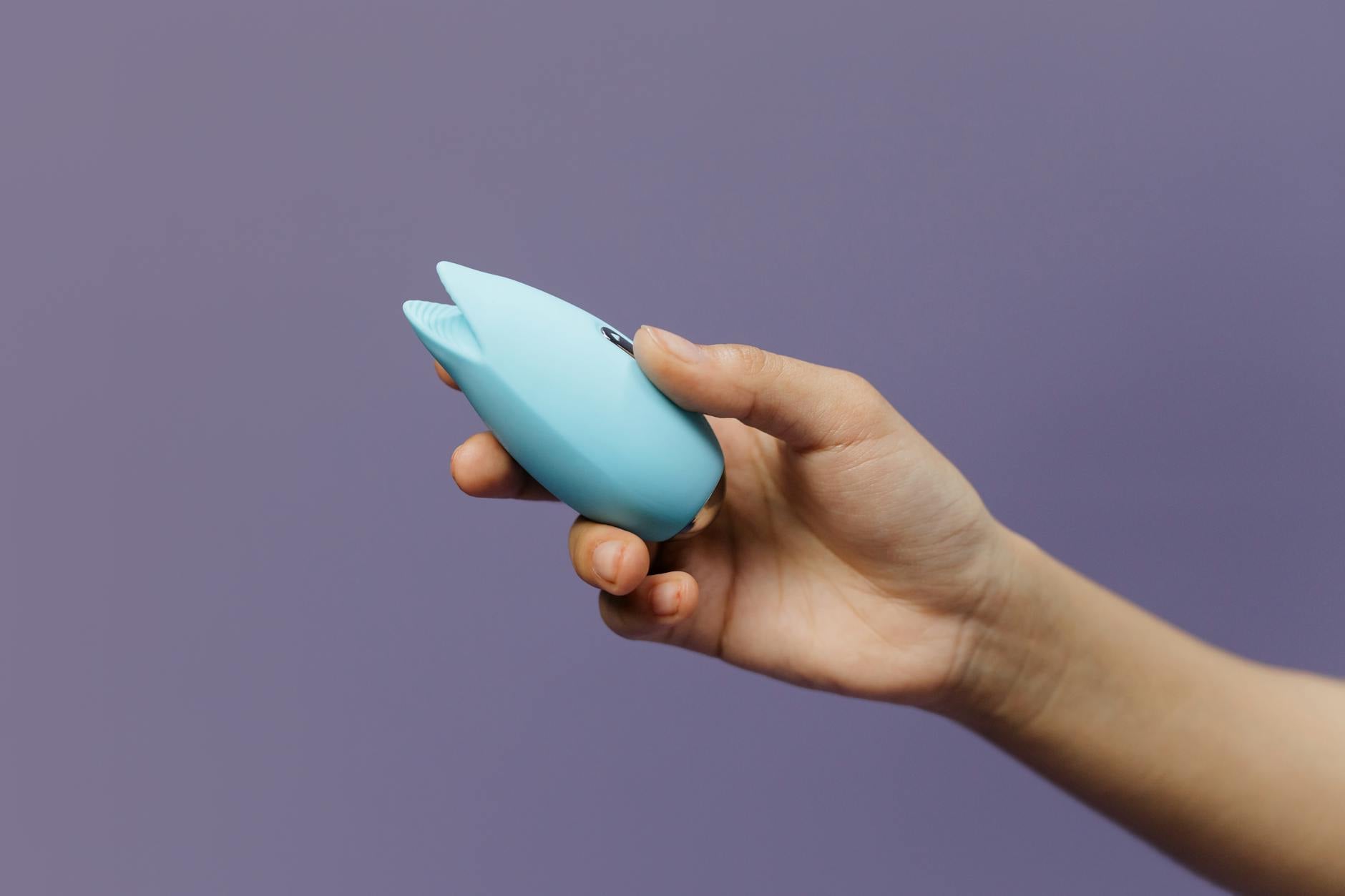 Woman holding blue and pink silicone vibrators, exploring different sensations and techniques